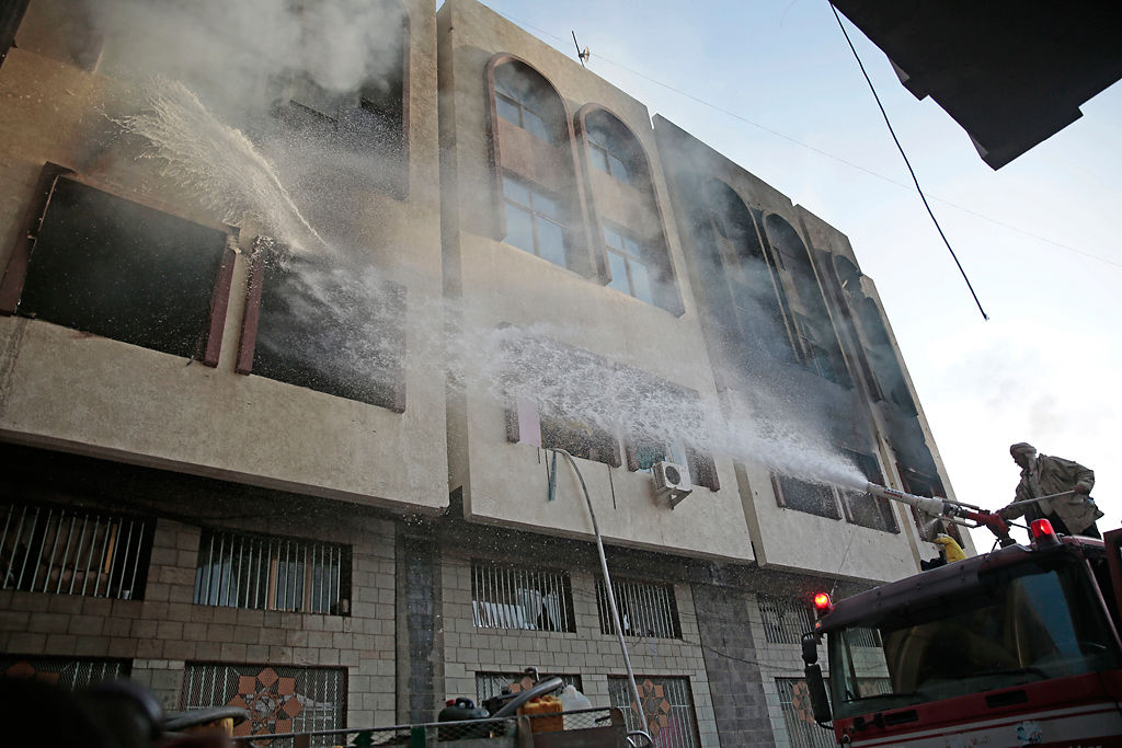 Firefighters work to extinguish a fire near the residence of the former Yemeni president